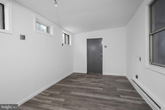 spare room featuring baseboard heating and dark hardwood / wood-style flooring