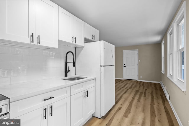 kitchen featuring sink, white cabinets, baseboard heating, and decorative backsplash