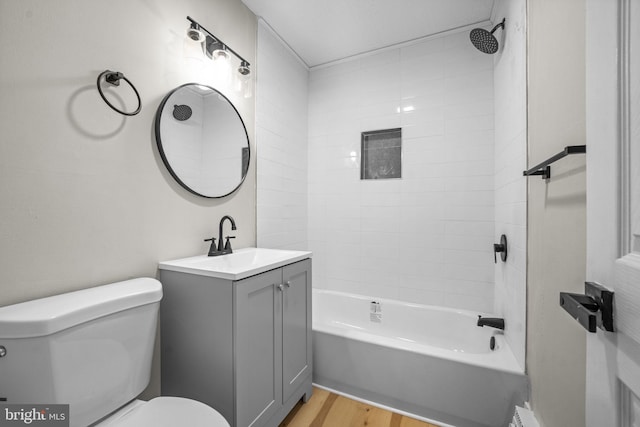 full bathroom with vanity, tiled shower / bath, hardwood / wood-style floors, and toilet