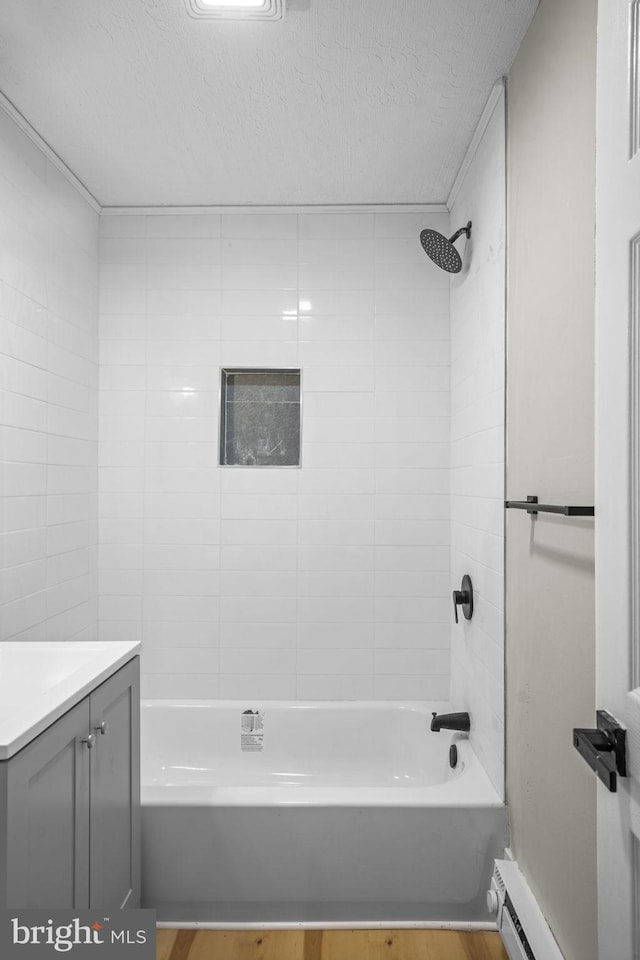 bathroom featuring hardwood / wood-style flooring, baseboard heating, tiled shower / bath combo, vanity, and a textured ceiling