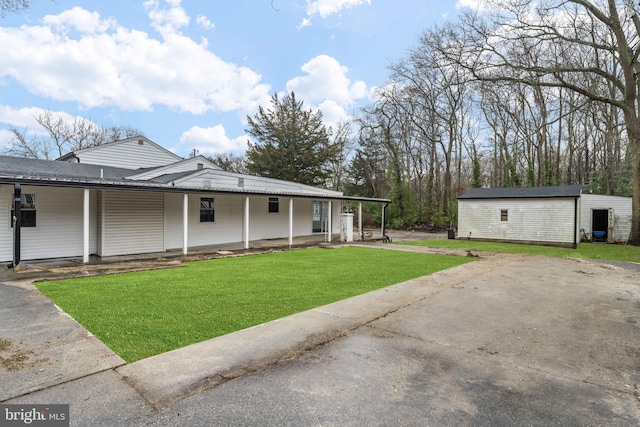 view of front of house with an outbuilding, a carport, and a front lawn