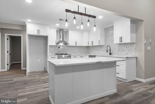 kitchen with white cabinetry, decorative light fixtures, stainless steel range, and wall chimney exhaust hood