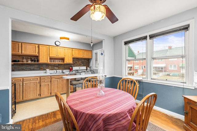 dining room with ceiling fan, sink, and light wood-type flooring