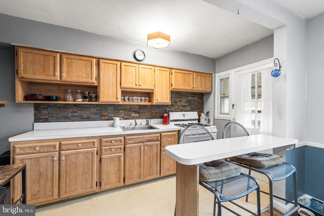 kitchen featuring a kitchen breakfast bar, sink, gas range gas stove, and backsplash