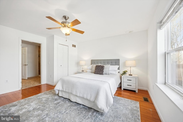 bedroom with ceiling fan, wood-type flooring, and a closet