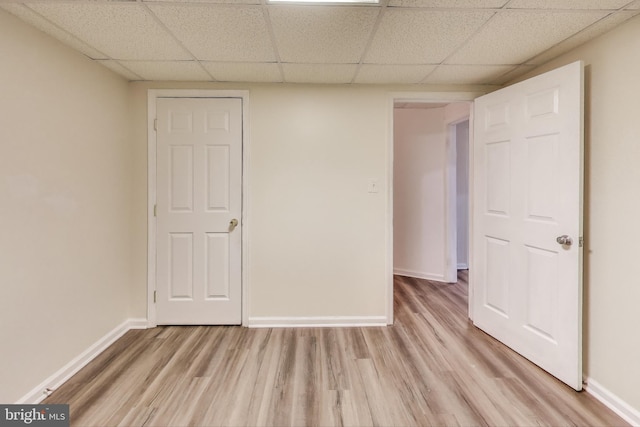 unfurnished room featuring a drop ceiling and light wood-type flooring