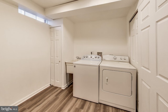 clothes washing area with wood-type flooring and independent washer and dryer