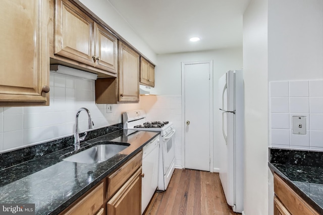 kitchen with tasteful backsplash, sink, dark stone countertops, light wood-type flooring, and white appliances