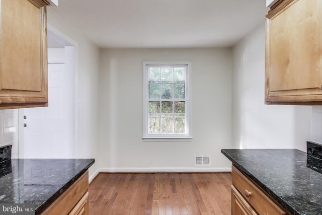 kitchen with light hardwood / wood-style flooring and dark stone counters