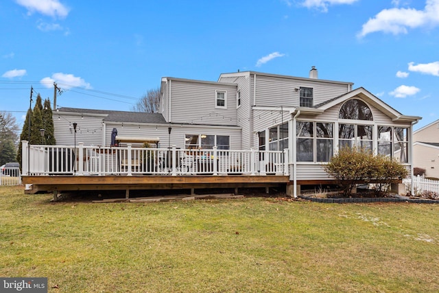 back of property featuring a wooden deck, a sunroom, and a lawn