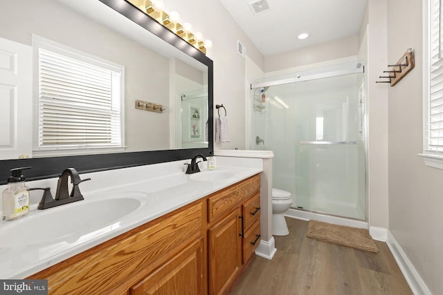 bathroom with an enclosed shower, vanity, hardwood / wood-style flooring, and toilet