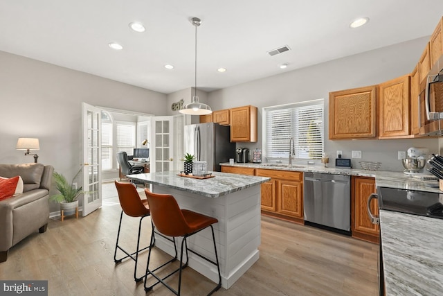 kitchen featuring sink, hanging light fixtures, stainless steel appliances, a kitchen island, and french doors