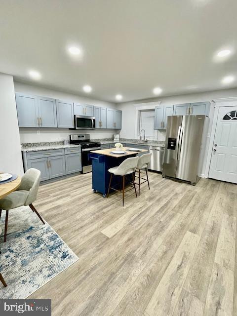 kitchen featuring gray cabinets, sink, a center island, stainless steel appliances, and light hardwood / wood-style flooring