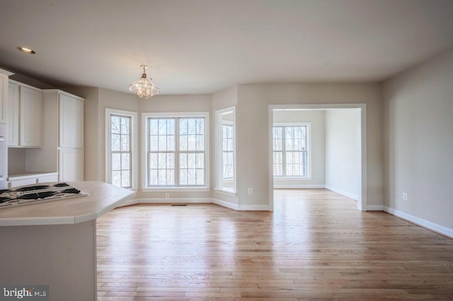 interior space with a notable chandelier, light hardwood / wood-style flooring, and plenty of natural light