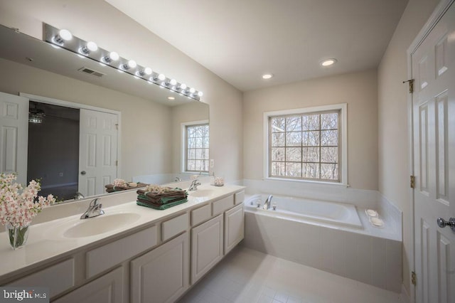 bathroom with a relaxing tiled tub and vanity