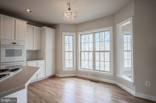 kitchen featuring light hardwood / wood-style flooring, hanging light fixtures, white double oven, a notable chandelier, and white cabinets