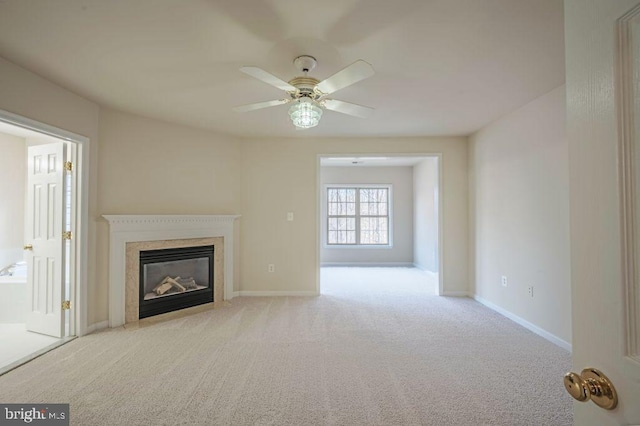 unfurnished living room featuring ceiling fan, light colored carpet, and a high end fireplace