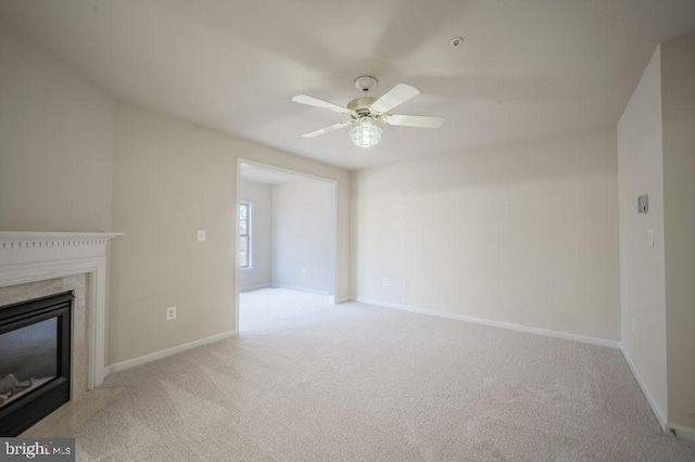 unfurnished living room with ceiling fan, a high end fireplace, and light carpet