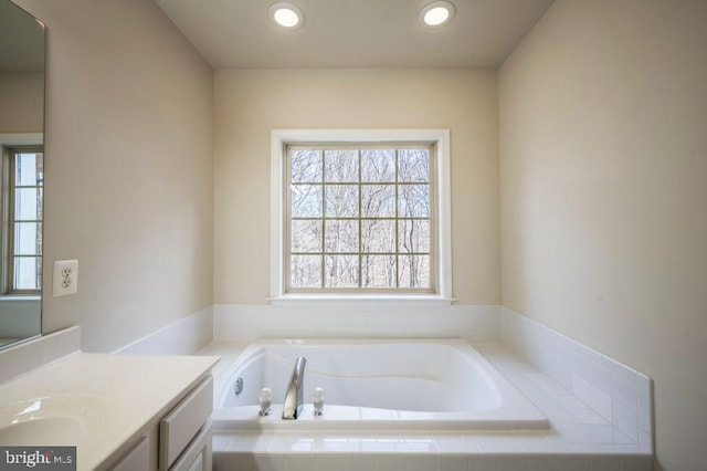 bathroom with vanity and tiled bath