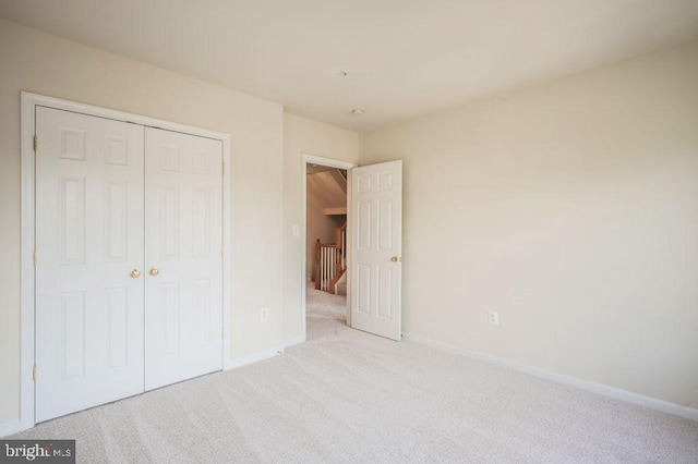 unfurnished bedroom featuring light carpet and a closet