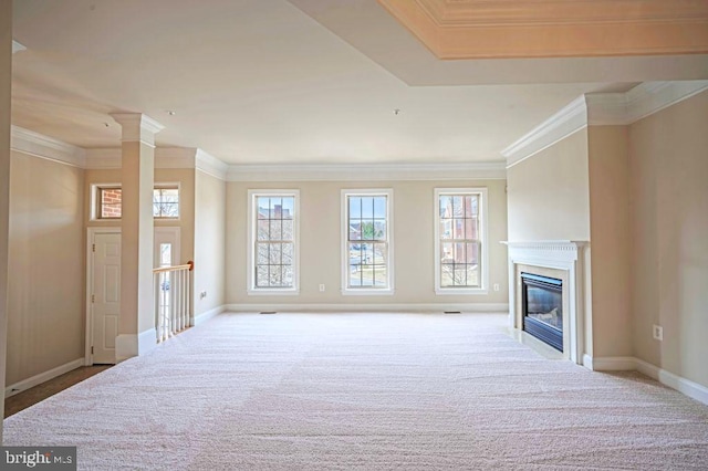 unfurnished living room with crown molding, a wealth of natural light, light colored carpet, and decorative columns