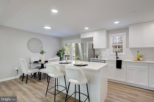 kitchen with stainless steel refrigerator, light hardwood / wood-style floors, sink, and white cabinets