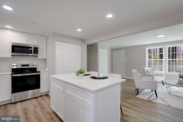 kitchen featuring light hardwood / wood-style flooring, a center island, white cabinets, and appliances with stainless steel finishes