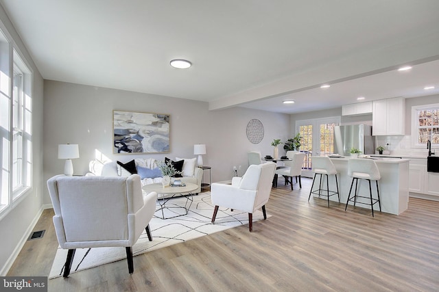 living room featuring beam ceiling and light hardwood / wood-style floors