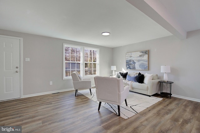 living room featuring beamed ceiling and light hardwood / wood-style flooring