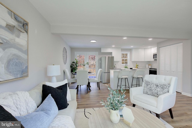 living room featuring beam ceiling and light hardwood / wood-style flooring