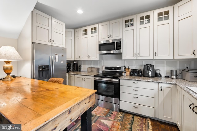 kitchen with appliances with stainless steel finishes, white cabinets, and light stone counters