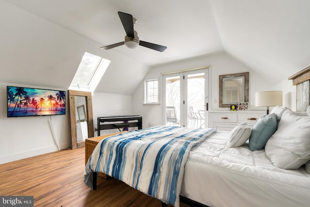 bedroom featuring hardwood / wood-style flooring, lofted ceiling with skylight, access to exterior, and ceiling fan