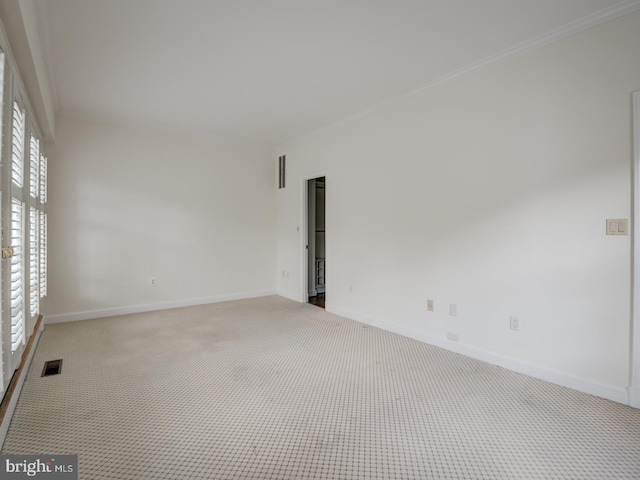 empty room featuring ornamental molding and carpet