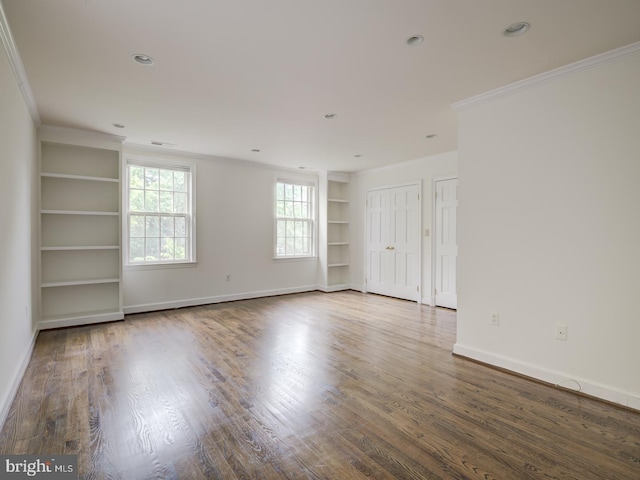 empty room with crown molding, built in features, and hardwood / wood-style flooring