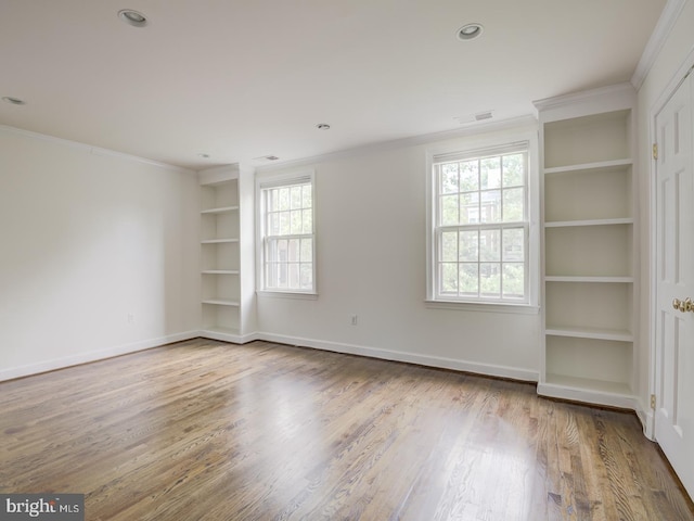 spare room with crown molding, wood-type flooring, and built in features