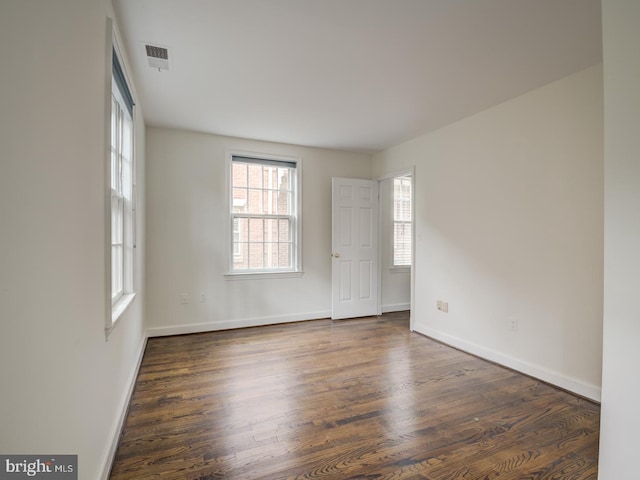 unfurnished room with dark hardwood / wood-style floors and a healthy amount of sunlight