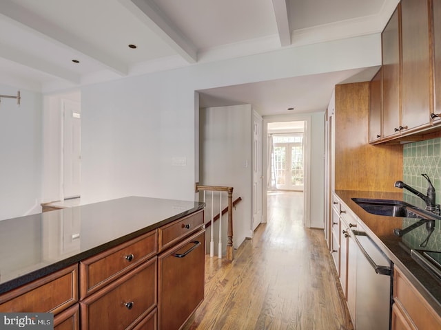 kitchen featuring sink, beam ceiling, decorative backsplash, stainless steel dishwasher, and light wood-type flooring