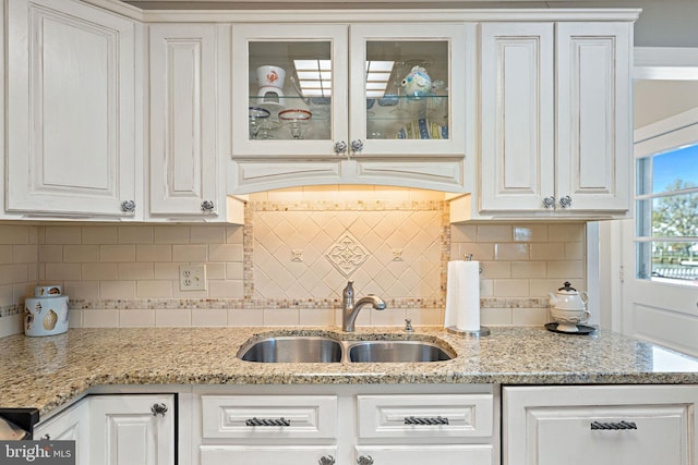 kitchen with white cabinetry, sink, and light stone counters