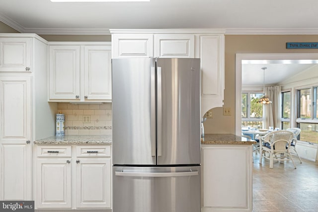 kitchen featuring white cabinetry, ornamental molding, stainless steel fridge, light stone countertops, and backsplash