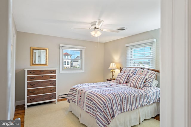 bedroom with multiple windows, a baseboard radiator, and ceiling fan