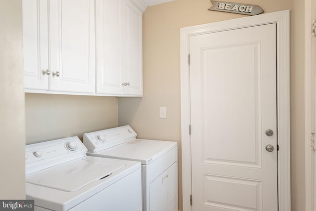 clothes washing area featuring cabinets and separate washer and dryer