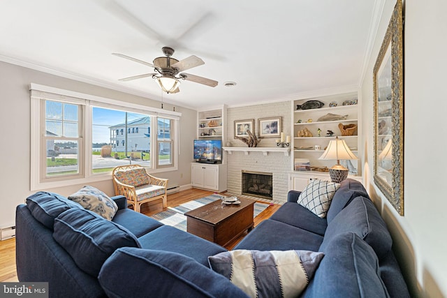 living room with a fireplace, hardwood / wood-style flooring, ceiling fan, crown molding, and built in shelves