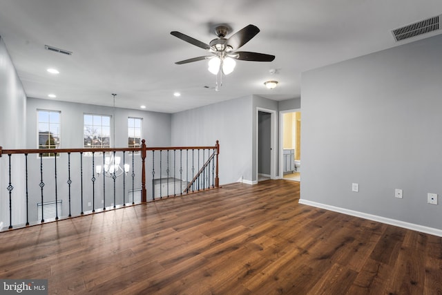 spare room featuring ceiling fan with notable chandelier and dark hardwood / wood-style floors