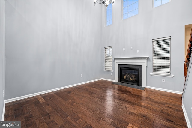 unfurnished living room featuring hardwood / wood-style floors, a high ceiling, and a notable chandelier