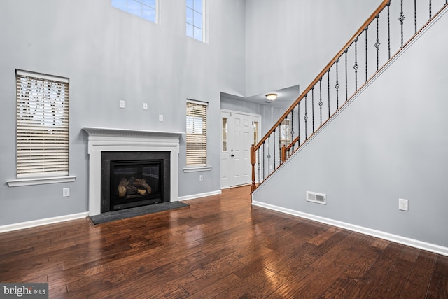 unfurnished living room with a towering ceiling and wood-type flooring