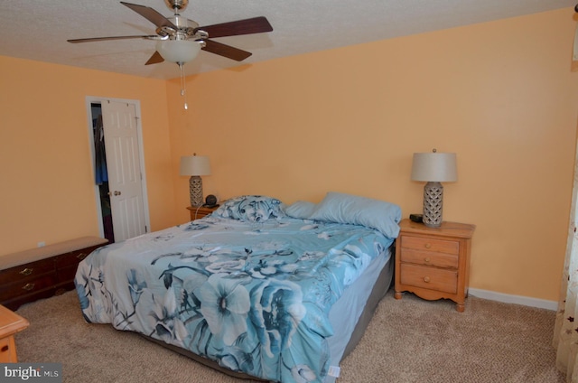 carpeted bedroom with ceiling fan and a textured ceiling