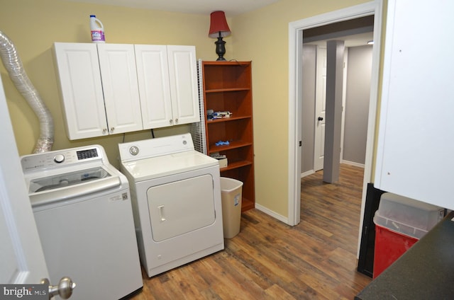 clothes washing area featuring dark hardwood / wood-style floors, washing machine and dryer, and cabinets