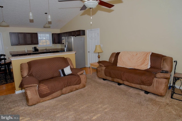 living room with lofted ceiling, sink, light hardwood / wood-style flooring, ceiling fan, and a textured ceiling