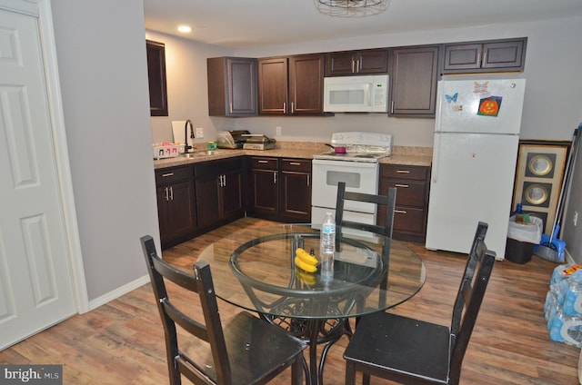 kitchen with dark brown cabinetry, sink, white appliances, and hardwood / wood-style flooring