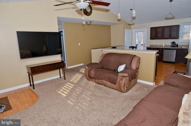 living room with lofted ceiling, light hardwood / wood-style flooring, ceiling fan, a wealth of natural light, and a textured ceiling